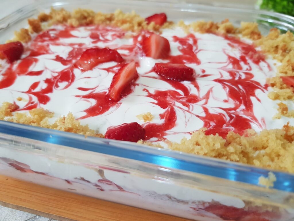 Creamy strawberry pudding served in a glass dessert cup, topped with fresh strawberry slices and a sprinkle of nuts